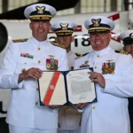 Coast Guard Rear Adm. Bob Little (left), commander of the Coast Guard Arctic District, poses for a photo with Capt. Timothy Williams (second to right), outgoing commanding officer of Air Station Kodiak. (U.S. Coast Guard photo by Petty Officer 3rd Class Rylan Singleton)