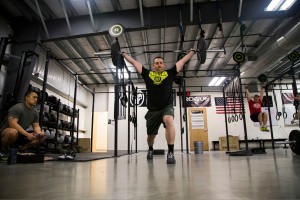 Chief Warrant Officer Mark Nieto, the property book officer for the 297th Battlefield Surveillance Battalion, Alaska Army National Guard, completes a clean and jerk movement during the 2015 CrossFit Open Games at the 907 CrossFit facility on Camp Carroll, February 27. Nieto is being scored by a CrossFit Level 1 instructor, 1st Lt. Danny Canlas, Jr.(U.S. Army National Guard photo by Sgt. Marisa Lindsay)