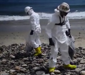 Hazmat-suited workers cleaning up tar-like crude from the Refugio State Beach. Image-USCG