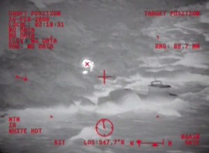 In this Coast Guard helicopter image, upon the Jayhawk's arrival,  the fisherman can be seen on shore with an ignited flare.