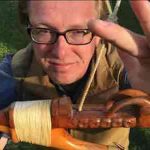 Jonathan Malidine displays a halibut hook made by Jon Rowan, a Tlingit master carver. The hook has caught fish; note the scratches from teeth on the lower arm.