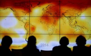 Participants seen in silhouette as they look at world map with climate anomalies. Image-Reuters/Stephane Mahe/File photo