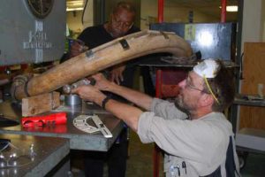 From left, Greg Shipman and Dale Pomraning of UAF’s Geophysical Institute cut a 20,000-year old mammoth tusk with a band saw. Photo by Pam Groves.