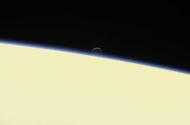 Saturn's active, ocean-bearing moon Enceladus sinks behind the giant planet in a farewell portrait from NASA's Cassini spacecraft. Credits: NASA/JPL-Caltech/Space Science Institute