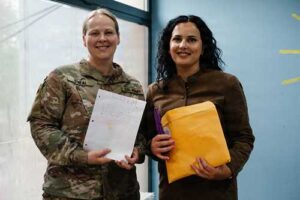 JOINT BASE ELMENDORF-RICHARDSON, Alaska - Alaska Army National Guard Capt. Balinda O’Neal, left, 134th Public Affairs Detachment commander, assigned to Kosovo Force (KFOR) Regional Command-East, presents letters to Festa Shabani, Future School program director, for students to participate in a pen pal exchange with youth in Alaska. (U.S. Army photo by Staff Sgt. Marc Marmeto)
