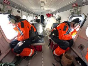 Observers Skyla Walcott and Tim Cole actively survey for bowhead and beluga whales, while Cynthia Christman records observation data on a laptop computer in the background. The observers use clinometers to measure the angle of the sighting. Knowing the altitude of the aircraft, they can calculate the horizontal distance of the whale from the aircraft, and record an accurate location of the animal. Credit: NOAA Fisheries / Paul Hillman
