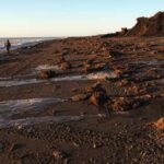 Photo by Alice Bailey A person walks along a storm-battered beach near Quinhagak after ex-Typhoon Merbok hit Western Alaska in 2022.