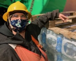 A Coast Guard Cutter Hickory crewmember stands next to a pallet of water bottles that were delivered to the residents of Angoon. Courtesy Photo U.S. Coast Guard District 17 