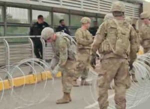 Troops laying out barbed-wire barrier at U.S./Mexico border. Image-Youtube screengrab