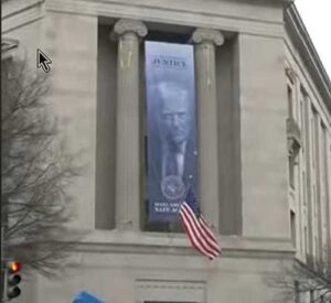 Enormous ‘Dictatorship-Style’ Banner With Trump Face on Side of Justice Department. Image-NBC video screengrab