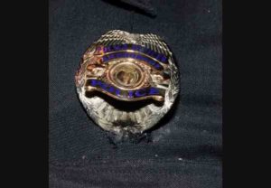 Image shows bullet damage to badge and body armor. Image-APD