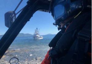 Coast Guard Lt. Dan Beshoar, an Air Station Kodiak MH-60 Jayhawk helicopter pilot, awaits the arrival of an injured fisherman via small boat from the fishing vessel Rubicon, near the Kupreonof Strait. Image courtesy of the USCG