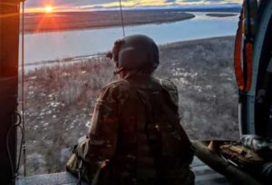 Sgt. Rosalind Stromberg, a crew chief from 1st Battalion, 207th Aviation Regiment, Alaska Army National Guard, looks over the Kuskokwim River from the door of a UH-60L Black Hawk helicopter during a rescue mission, May 10. (Courtesy photo by Spc. Kia Hasson)