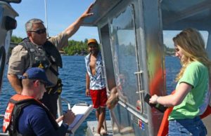 Tom Akelkok (upper left), law enforcement officer with Alaska Wildlife Troopers, and Lt.j.g. Scott Peters, boarding officer with Coast Guard Sector Anchorage, conduct a vessel safety inspection on Big Lake. U.S. Coast Guard photo by PA1 Nate Littlejohn