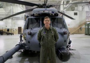 U.S. Air Force Captain Seth Peterson, a helicopter pilot assigned to the 210th Rescue Squadron, Joint Base Elemendorf-Richardson, Alaska, stands in front of an HH-60G Pave Hawk helicopter in a hanger at JBER. (U.S. Air National Guard photo by Staff Sgt. Kelly Willett/Released)