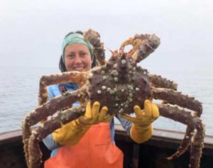 Erin Fedewa holds up a king crab with barnacles on its back. Credit: NOAA Fisheries