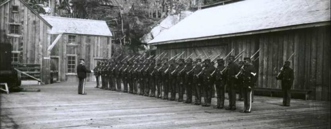 Company L stands at attention on the Dyea-Klondike wharf in Dyea, Alaska 1899. Photo courtesy of the Alaska State Library William Norton Collection (ASL-P226-868)