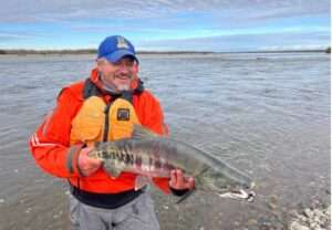 Peter Westley holds a spawning male chum salmon alongside the Anaktuvuk River. Photo by Joe Spencer/ADF&G