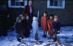 Photo: Joyce Smith and Larsen Bay children with a snow man. Smith Collection, courtesy of Tim and Norman Smith.