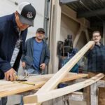 Photo by Nathaniel Wilder Participants in a 2024 lumber grading certification training course check a piece of structural lumber for warp or other defects.