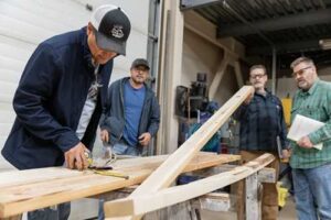 Photo by Nathaniel Wilder
Participants in a 2024 lumber grading certification training course check a piece of structural lumber for warp or other defects.