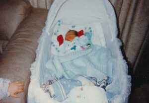 Photo: Baby in basinet, Akhiok, ca. 1995. Courtesy of Doreen Phillips.
