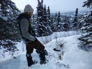 Photo by Carl Tape. UAF graduate student Cole Richards installs a high-sampling seismic sensor in February 2019. It is one 400 placed along the Parks Highway following the 2018 magnitude 7.1 Anchorage earthquake. Graduate student Bella Seppi would later use the sensor data in her aircraft research.