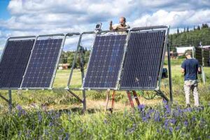 Photo by Jeff Fisher. ACEP’s Cole Sudkamp-Walker works on a solar panel at the Solar Photovoltaic Test Site on the University of Alaska Fairbanks Troth Yeddha’ campus.
