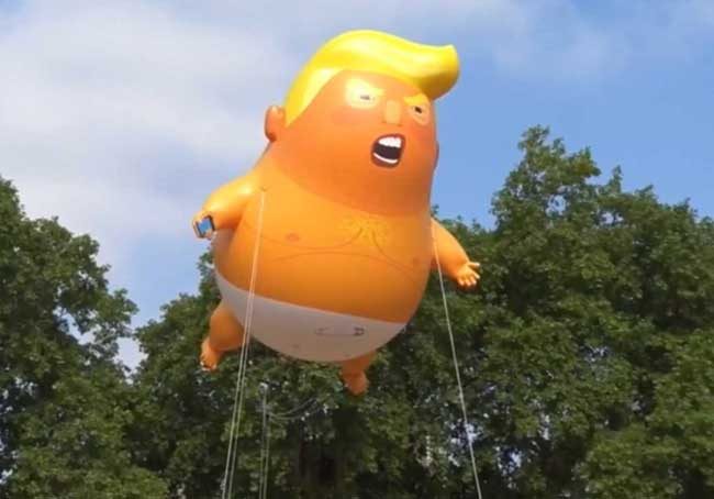 Snarling orange Trump baby blimp complete with cell phone flying at Great Britain's parliament. Image-Reuters video screengrab