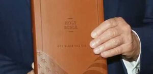 President Donald Trump holds a “Good Bless the USA Bible,” a licensed product that he has earned $1.5 million from. (Photo via Lee Greenwood/YouTube)
