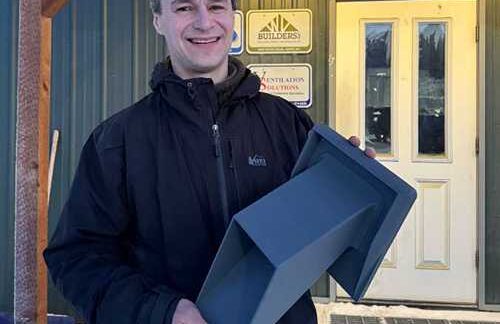 Photo by Molly Simons Tom Marsik holds an Arctic Dual Hood he and his team developed in front of Ventilation Solutions in Fairbanks, where the hoods are now available. Arctic Dual Hood simplifies energy-efficient ventilation